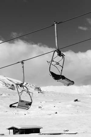 Snowy slope, ski-lift and sky with clouds at sunny winter day. Caucasus Mountains, Shahdagh, Azerbaijan. Black and white toned image. High contrast.の写真素材