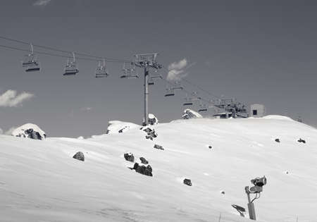 Chair-lift and snowy slope with snowmaking at ski resort on sun day. Caucasus Mountains in winter, Shahdagh, Azerbaijan. Black and white retro toned landscape.の写真素材