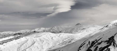 Panorama of snowy high mountains and cloudy sky at sun winter evening. Caucasus Mountains, Shahdagh, Azerbaijan. Black and white toned landscape.の写真素材