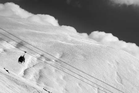 Black and white view of gondola lift and off-piste slope at evening