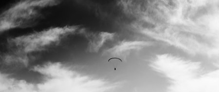 Panoramic view on silhouette of skydiver at windy sky. Black and white toned image.の写真素材