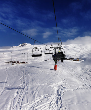 Chair-lift and off-piste slope with trace from skis and snowboards in high winter mountains. Caucasus Mountains, Georgia, region Gudauri.の写真素材