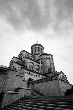 Tsminda Sameba Cathedral or Holy Trinity Cathedral and cloudy gray sky. Main cathedral of Georgian Orthodox Church located in Tbilisi capital of Georgia. Black and white wide angle view. High contrastの写真素材