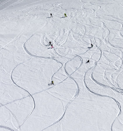 Snowboarders and skiers descend on snowy off-piste slope at high winter mountains. View from above.の写真素材