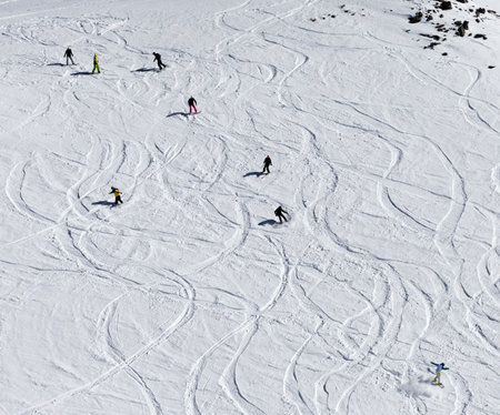 Snowboarders and skiers downhill on snowy off piste slope. High winter mountains. Top view.の写真素材