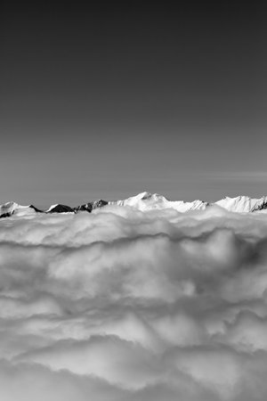 High snowy mountains under clouds at winter evening. Caucasus Mountains, Georgia, region Gudauri. View from ski slope. Black and white toned landscape.の写真素材