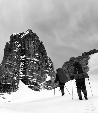 Two hikers in snowy mountains before storm. Turkey, Central Taurus Mountains, Aladaglar, plateau Edigel (Yedi Goller). Black and white toned landscapeの写真素材