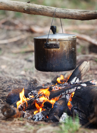 Outdoor cooking in old sooty cauldron on campfire at forest. Close-up view.の写真素材