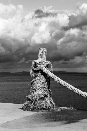 Rope on seafront, sea and beautiful cloudy sky in sunny summer day. Turkey, Erdek, coast of Marmara. Black and white toned landscape. High contrast.の写真素材