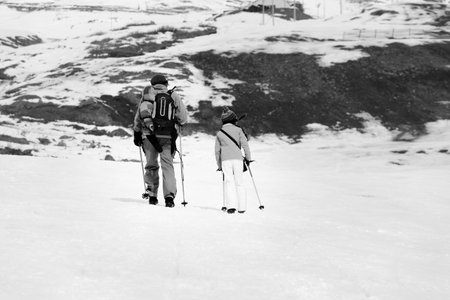 Father and daughter with ski poles on snowy slope in little snow winter. Caucasus Mountains,...