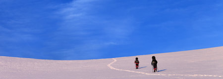Two hikers on sunrise snowy plateau in high mountains. Turkey, Central Taurus Mountains, Aladaglar (Anti-Taurus) plateau Edigel (Yedi Goller). Panoramic view. Remote location.の写真素材