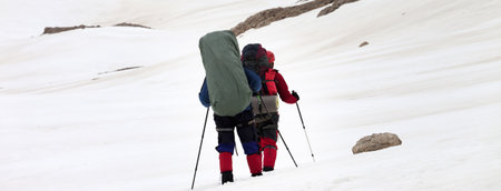 Two hikers on snowy plateau at gray day. Turkey, Central Taurus Mountains, Aladaglar, Anti Taurus, plateau Edigel, Yedi Goller. Remote location. Panoramic view.の写真素材