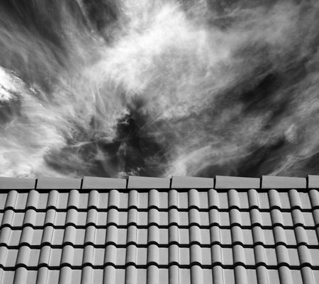 Roof tiles and sky with clouds at sun day. Black and white toned image.
