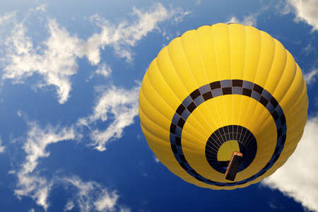 Yellow hot air balloon on blue sunlight sky with clouds. Bottom view.の写真素材
