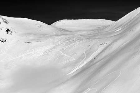 Snow off-piste slope with traces of skis, snowboards and avalanches. Caucasus Mountains in winter, Georgia, region Gudauri. Black and white toned landscape.の写真素材