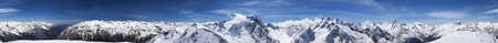 Cylindrical panorama 360 degrees of high snow-capped mountain peaks and beautiful blue sky with clouds at sunny day. Caucasus Mountains in winter, region Dombay.の写真素材