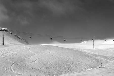 Gondola lift and off-piste ski slope in fog at nice sunny evening. Caucasus Mountains in winter, Georgia, region Gudauri. Black and white toned image.の写真素材