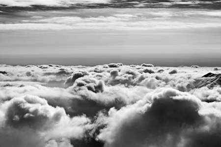 Black and white snowy high mountains covered with beautiful sunlight clouds at sunny winter evening. Caucasus Mountains, Georgia, region Gudauri. High contrast.の写真素材