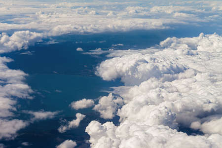 Airplane view on clouds and sea in sun summer dayの写真素材