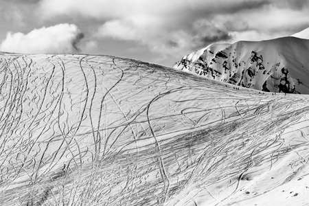Snow off piste slope for freeriding with traces from skis, snowboards at sunny winter day. Caucasus Mountains, Georgia, region Gudauri. Black and white toned landscape. High contrast.の写真素材