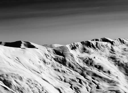 View on off-piste snowy sunlight slope at winter evening. Caucasus Mountains, Georgia, region Gudauri. Black and white toned landscape. High contrast.の写真素材