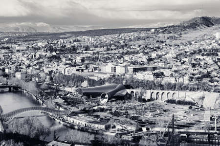 Center of Tbilisi, capital of Georgia on sunny day. View on Rike park, modern Concert Hall, Presidential Administration, Kura river, Bridge of Peace and mountains. Black and white. High contrast.の写真素材