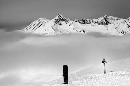 Warning sing, snowboard on off-piste and mountains in fog. Caucasus Mountains, Georgia, ski resort Gudauri. Black and white toned landscape.の写真素材