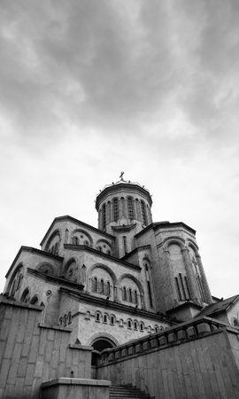 Tsminda Sameba Cathedral or Holy Trinity Cathedral and cloudy gray sky. Main cathedral of Georgian Orthodox Church located in Tbilisi capital of Georgia. Black and white wide angle view. High contrastの写真素材