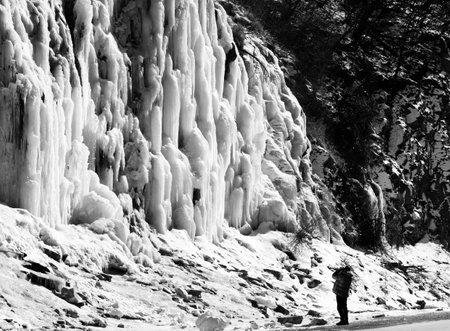 Man makes photo of icy mountain waterfall at nice sun day. Winter in Georgia. Black and white toned image.の写真素材