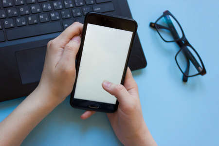 man works at a laptop and holds a phone in his hand flatly.the problem of concentration at work...