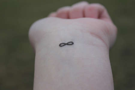 closeup of the arm with an infinity symbol tattooed in his wrist. infinity sign on the hand. endless love conceptの写真素材