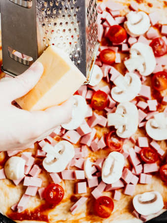 homemade pizza step by step instruction.DIY pizza step 6.cooking, food and home concept - close up of female hands grating cheeseの写真素材
