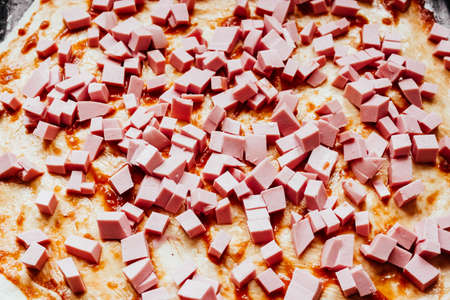 homemade pizza step by step instruction.DIY pizza step 4. put the sausage on the pizza dough. Female making pizza, putting cut sausage on the dough with sauce. Top view.の写真素材