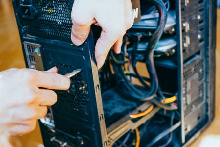 Senior male tech works in hardware repair facility.guy is assembling a computer.