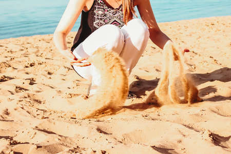 woman Hands holding and spilling sand on the beach.Very shallow depth-of-field and motion blur.girl pouring sand from the palms.の写真素材