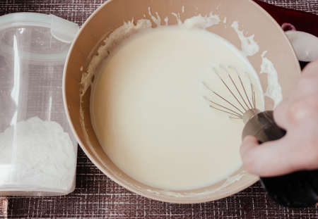 Dough for making pancakes or omelet in a bowl with a whisk in the kitchen.homemade healthy pancakes made from cottage cheese. pancakes instruction step by step.step 1 making dough for pancakes.の写真素材