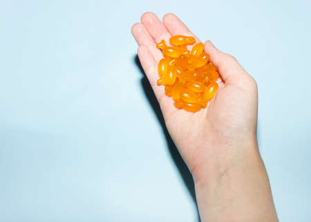 Dietary supplements. Omega 3 capsules in fish shape on blue background. Flat lay. Health support and treatment. Biologically active additives. DHA, EPAの写真素材