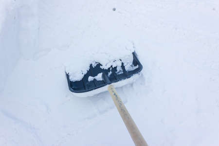 a large pile of snow with a shovel stuck in. snow removal. large amount of precipitation in winterの写真素材