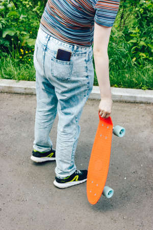 close up stylish girl carrying the penny board in the summer city parkの写真素材