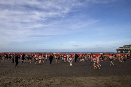 SCHEVENINGEN, 1 January 2018 - Dutch people following the strong tradition of the first new year dive runs toward the frozen North Sea water after the midday ring bellsのeditorial素材