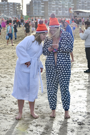 SCHEVENINGEN, 1 January 2018 - A mother and her daughter reviewing pictures on her phone captured during their first new year dip in the frozen North Sea water, The Netherlandsのeditorial素材