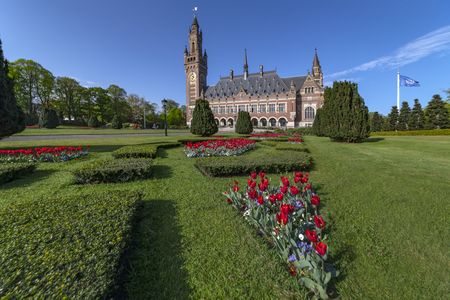 THE HAGUE, 24 April 2019 - Sunrise at the Peace Palace, seat of the International Court of Justice, view from the peaceful garden with read tulip flowers around the buildingのeditorial素材
