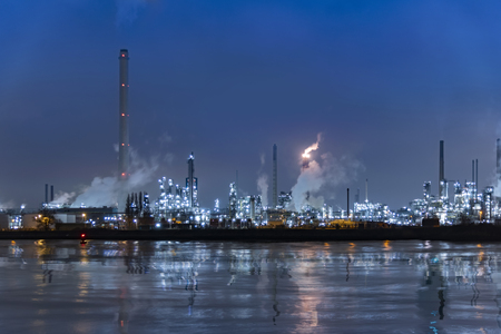 Reflection of refineries and its chimney during the on fire sunset golden hour moment at Rotterdam, Netherlandsの写真素材