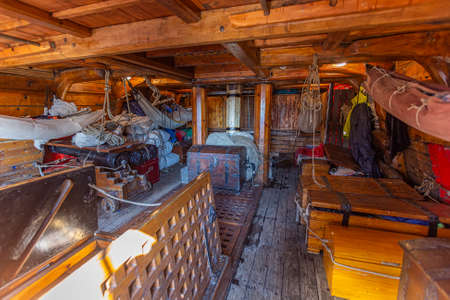 Inner view of a wooden pirate tall ship cabin with canon, chest and folded wings ready to sail away campaigning on the high seaのeditorial素材