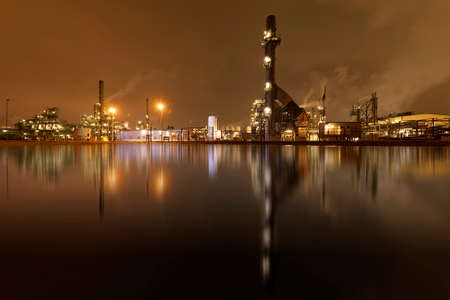 Refineries reflection and its chimney during the on fire sunset golden hour moment at Rotterdam, Netherlandsのeditorial素材