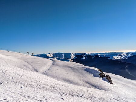 Snowy slopes at 2000 m in Sinaia on a sunny day with clear blue sky.