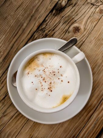 Cup of Cappuccino topped with Cocoa; seen from above and on a wooden table.の写真素材