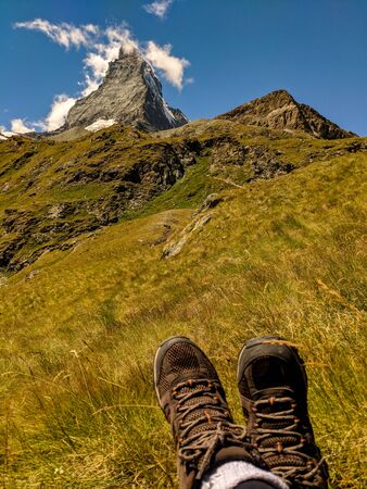 Wonderful view of Matterhorn with hiking boots in the foregroundの写真素材