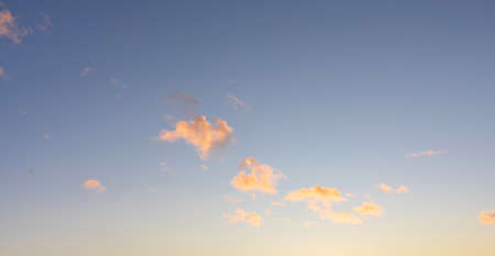 Blue sky with curly clouds and sun, sunset with sun rays. landscape background
