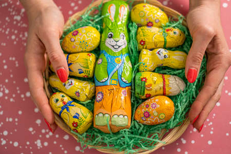 Easter decorative chocolate eggs and bunny in a basket on a red backgroundの写真素材